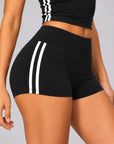 Close-up of black sculpt shorts showing double white side stripes and high waistband